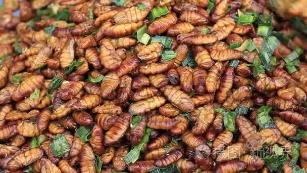 食用烤五香膳食蠕虫，泰国街头食品煎炸的 Bug。炒幼虫是泰国市场上的食物