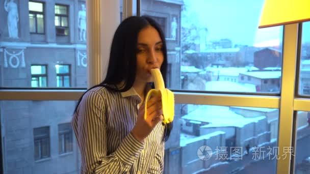 可爱的女孩很好地吃一根香蕉和微笑