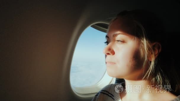 年轻女子坐在一架飞机。坐在敞开的窗户，可以看到天空中视频