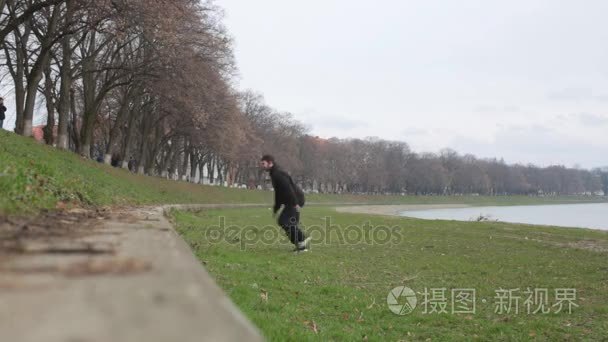 年轻的男孩制作跑酷运动对河堤视频