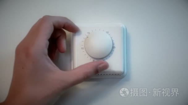 调整室内墙体温控器的男人视频