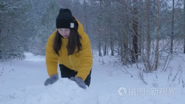 一个女孩造型在冬天在雪地里堆雪人