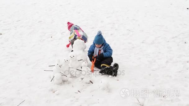 小男孩和女孩在冬天建设雪人