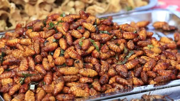 食用烤五香膳食蠕虫，泰国街头食品煎炸的 Bug。炒幼虫是上泰国市场特写的食物