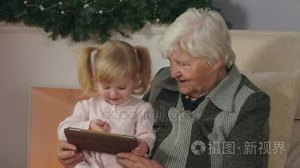 女孩和她的祖母看着平板电脑照片