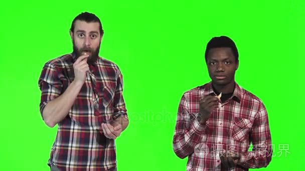 两个男人在绿色屏幕上吃薯条