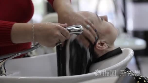 洗在美发沙龙中的客户端头发的理发师