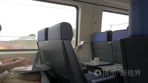 在通勤列车中使用手机和笔记本电脑的男人