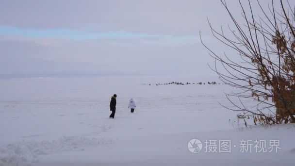 孩子回来后从覆盖着冰的湖。男孩和女孩走在冰面上的一个大湖。湖面上覆盖着大量的雪视频