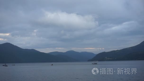 在黄昏的渔船在距离山湖视频