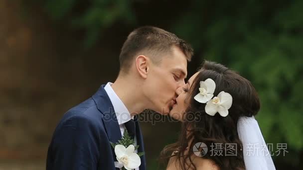 高新郎亲吻新娘与白色兰花在她的头发