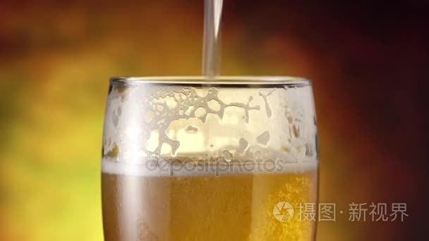 啤酒从顶部注入玻璃。4 k 视频