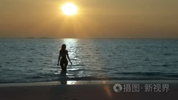女人在日落时分离开大海的剪影视频