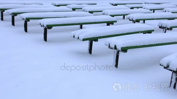 大雪后完全被雪覆盖的公园里的长凳。雪后降雪沉积在公园里的长凳上