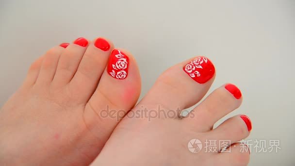 女性的脚与红色指甲油和花卉图案
