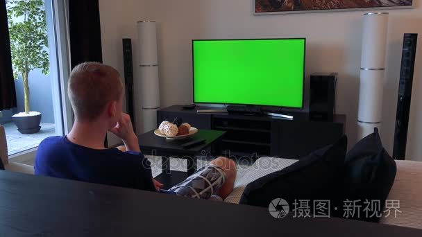 一个人看电视与绿屏在舒适的客厅里,最终看起来带走短视频