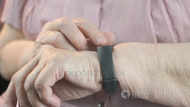 老年妇女触动腕带的脉搏监测仪