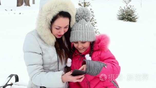 两个女孩，母亲和女儿，在严寒的冬日投掷一个公园的雪