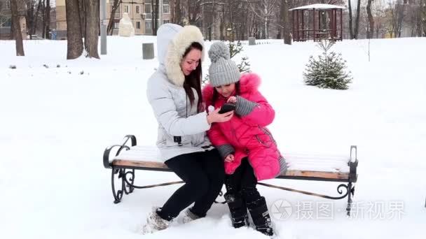 两个女孩，母亲和女儿，在严寒的冬日投掷一个公园的雪