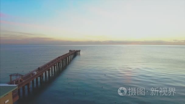 日出时海滩和码头的空中飞行