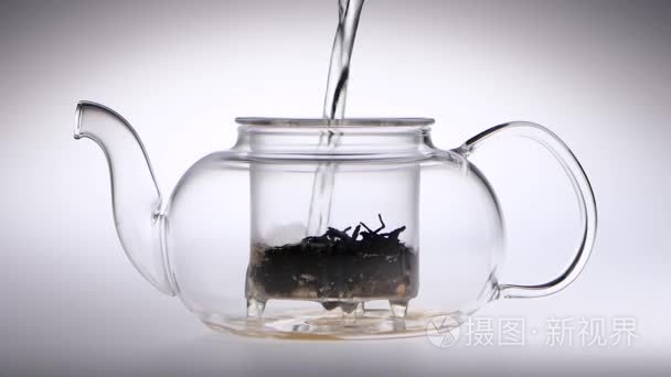 沸腾的水倒入茶树叶透明茶壶视频