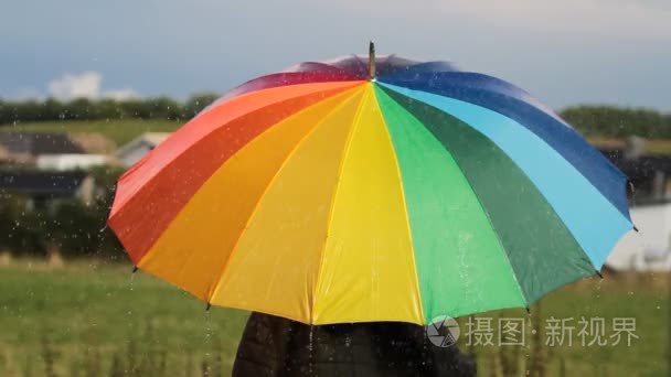 一个人与彩虹彩色伞在雨中视频