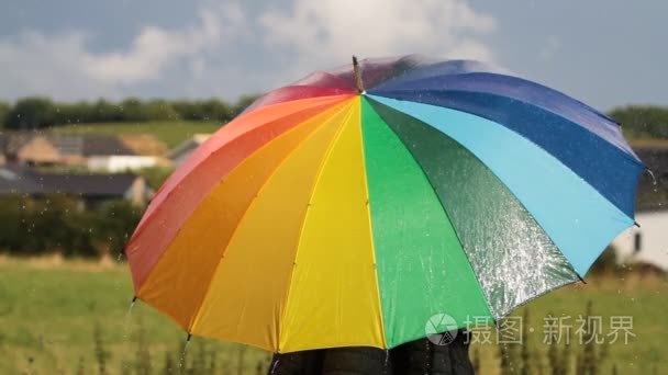 一个人与彩虹彩色伞在雨中视频