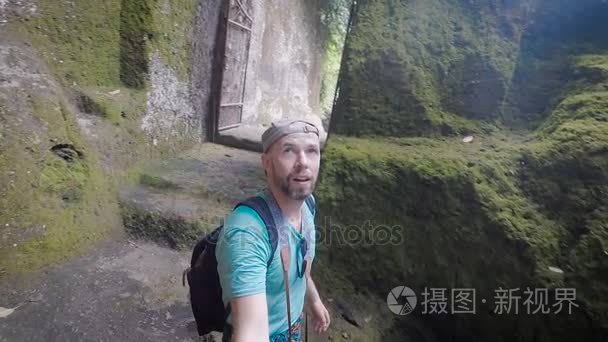 年轻男子走过难以置信的美丽岛和惊喜认为景点和美丽的风景。旅游拍摄视频在记忆的旅途大棒政策自拍照视频