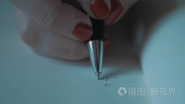 用笔在白纸上关闭了慢动作女人手红色指甲油写作