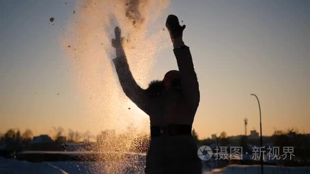 一个女孩抛雪她头顶上日落背景