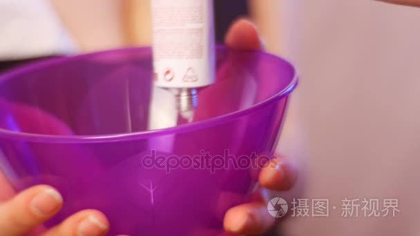 发型师挤管头发造型师准备在紫色染料染色的染料碗 Haircolor 提示和技巧设计师经验丰富业余爱好