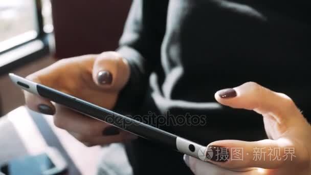 一个女孩在平板电脑上写一条消息。互联网通讯和社会服务。女性手里拿着电话