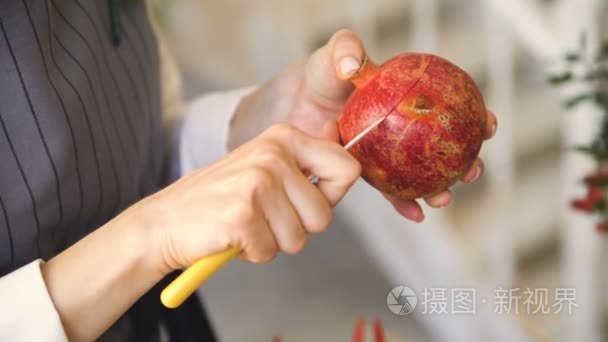 厨师女人在围裙切石榴与刀特写在厨房里做菜