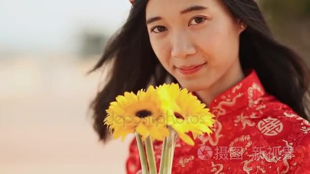 美丽的越南女孩穿着红色传统 Ao Dai，花黄色。特写