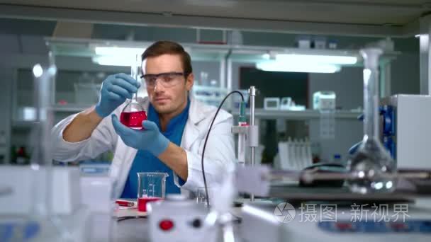 学习在现代实验室玻璃烧瓶中的液体的化学家。实验室工作人员