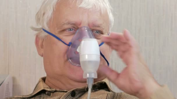 一位老人在家里举行一个面具从吸入器.对待通过雾化器呼吸道炎症.