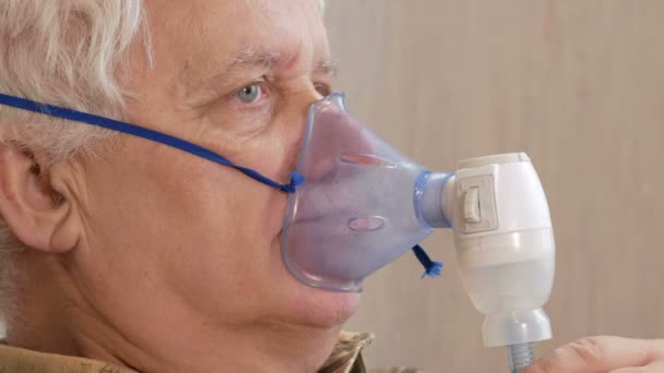 一位老人在家里举行一个面具从吸入器.对待通过雾化器呼吸道炎症.