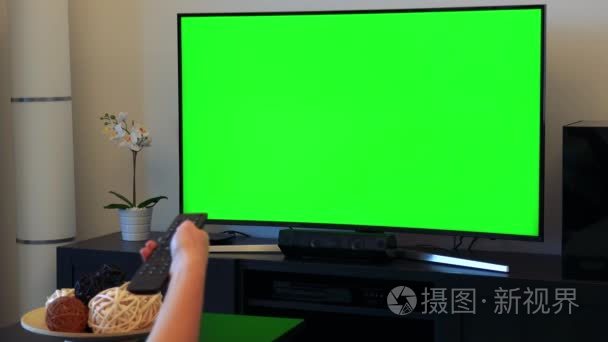 一个女人绿屏电视上切换频道