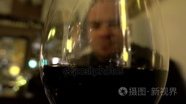 模糊视图通过杯红酒的一个孤独的人在酒吧
