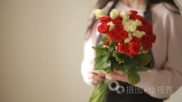 光明华美的红色和白色的玫瑰花束，花店女人收集一束