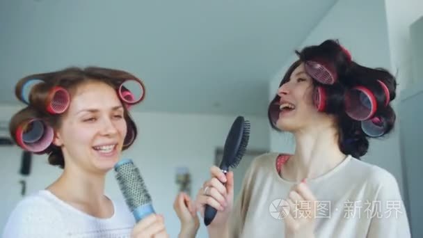 两个有趣的女孩歌唱与梳子跳舞和在家里的客厅里有欢乐视频
