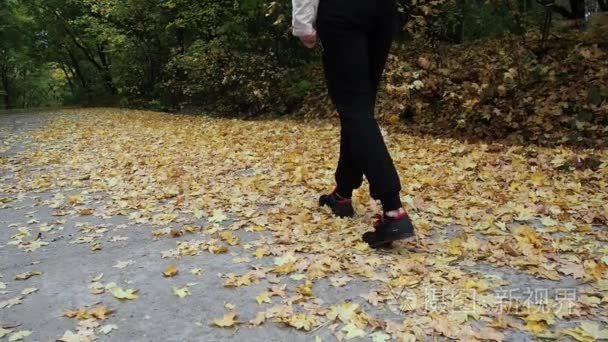 背包的女孩走在黄色的树叶上