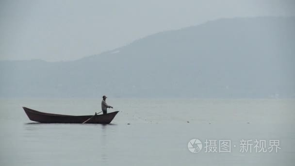 小船上捉鱼在湖高背景的雾山人视频