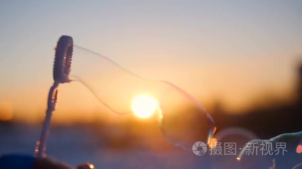 在严寒的冬日夕阳的背景上的美丽肥皂泡泡。