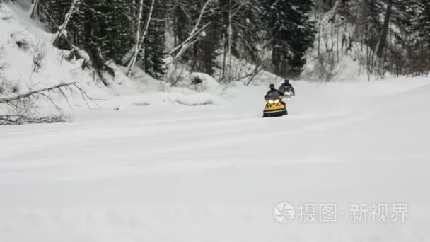 两辆雪地车骑在冰冻的河