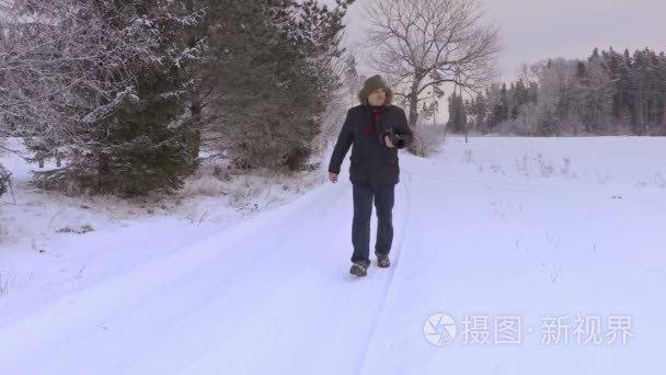 专业摄影相机在冬天积雪覆盖的道路上的人