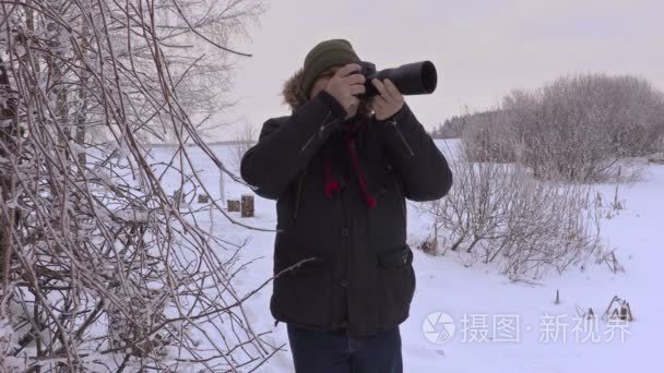 男人在冬天专业摄影相机拍照片视频