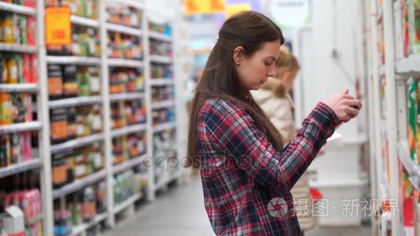 画面的女人买果汁在超市。4 k 视频