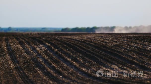 领域的高端黑土。为种植季节做准备。远从拖拉机的工作领域中的尘埃云视频