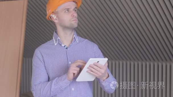 看着他在高层建筑施工中的数字平板电脑屏幕的男性构架